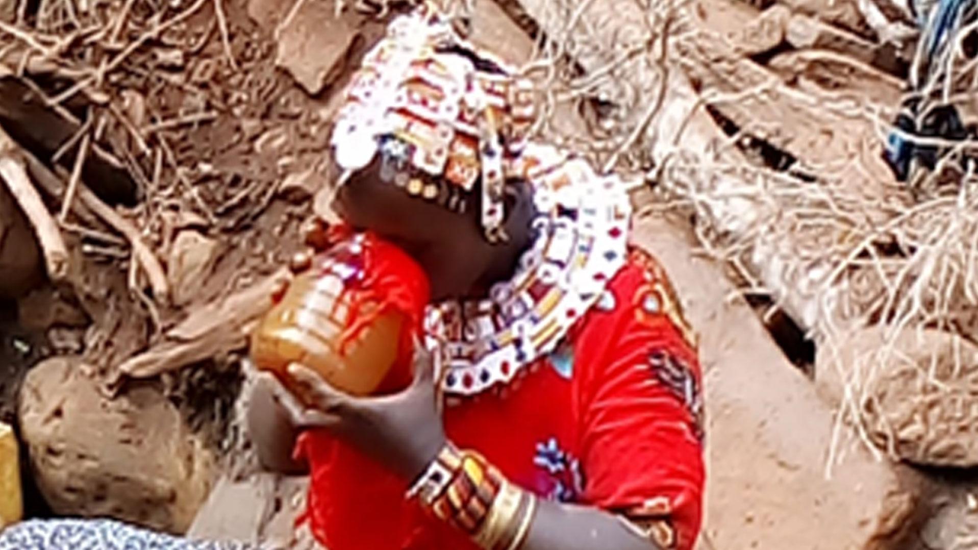 Samburu woman drinking (brownish) well water filtered through the fabric of her dress