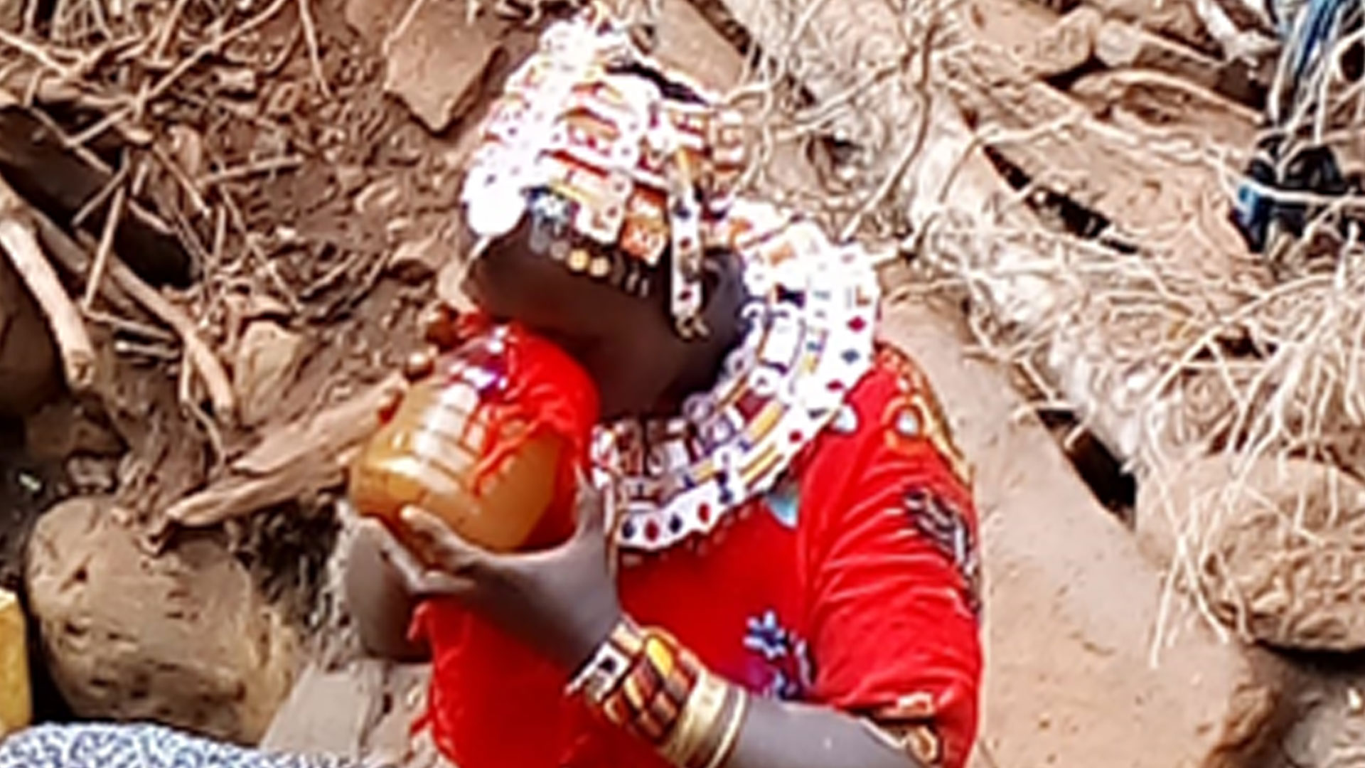 Samburu woman drinking (brownish) well water filtered through the fabric of her dress